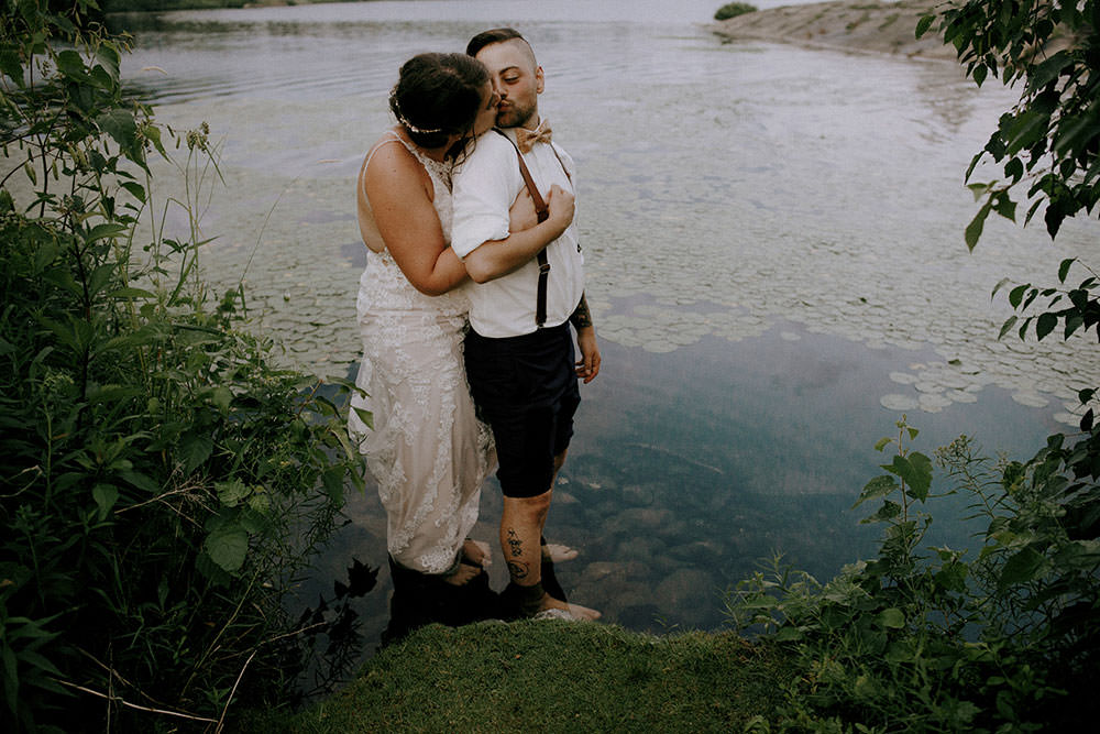 bride and groom standing in pond on wedding evening