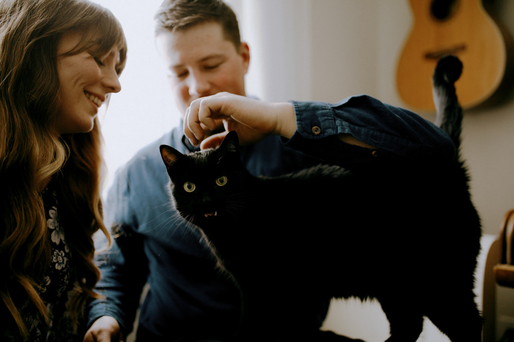 couple plays with cat in engagement photography session in their innisfil home