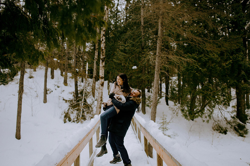 couple plays in snow on trail in ontario engagement session