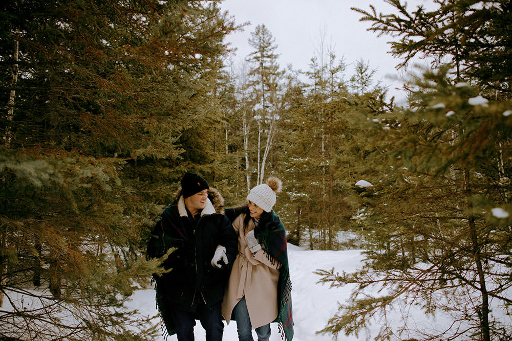 couple plays in snow on trail in ontario engagement session
