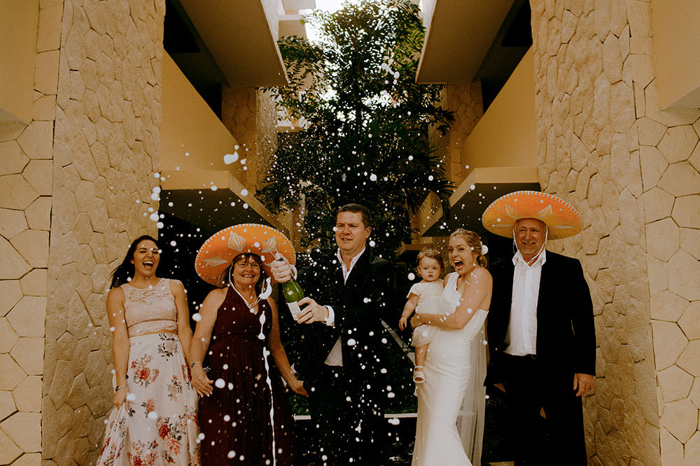 Royalton Riviera Cancun Wedding party pops champagne bottle