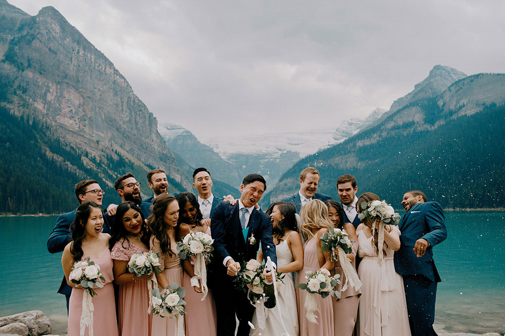 fairmont lake louise bridal party portrait of them popping champagne bottle in celebration