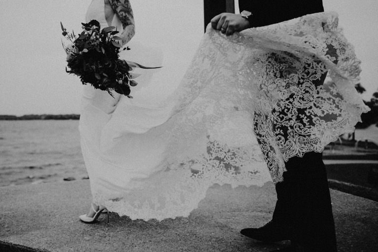 Barrie Ontario wedding photography of groom holding brides dress in the wind