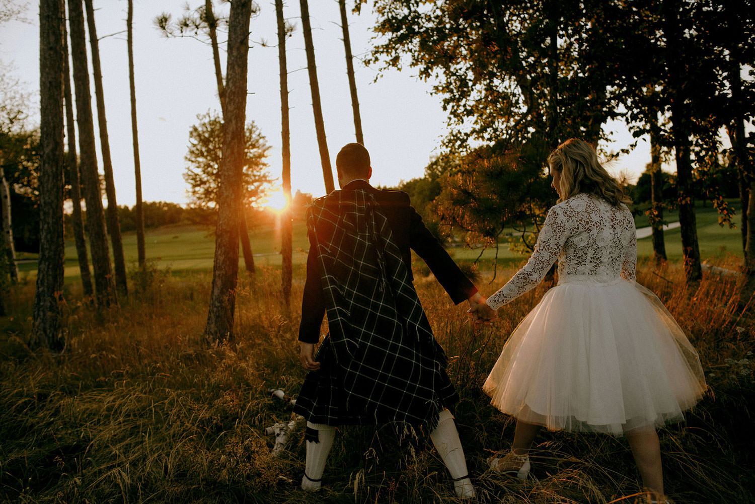 sudbury Ontario idylwylde wedding photography of bride and groom walking hand in hand at sunset hour in the forest