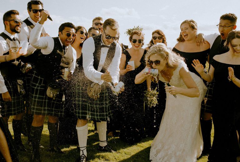 sudbury Ontario idylwylde wedding photography of bride and groom shot gunning beer surrounded by the cheering bridal party