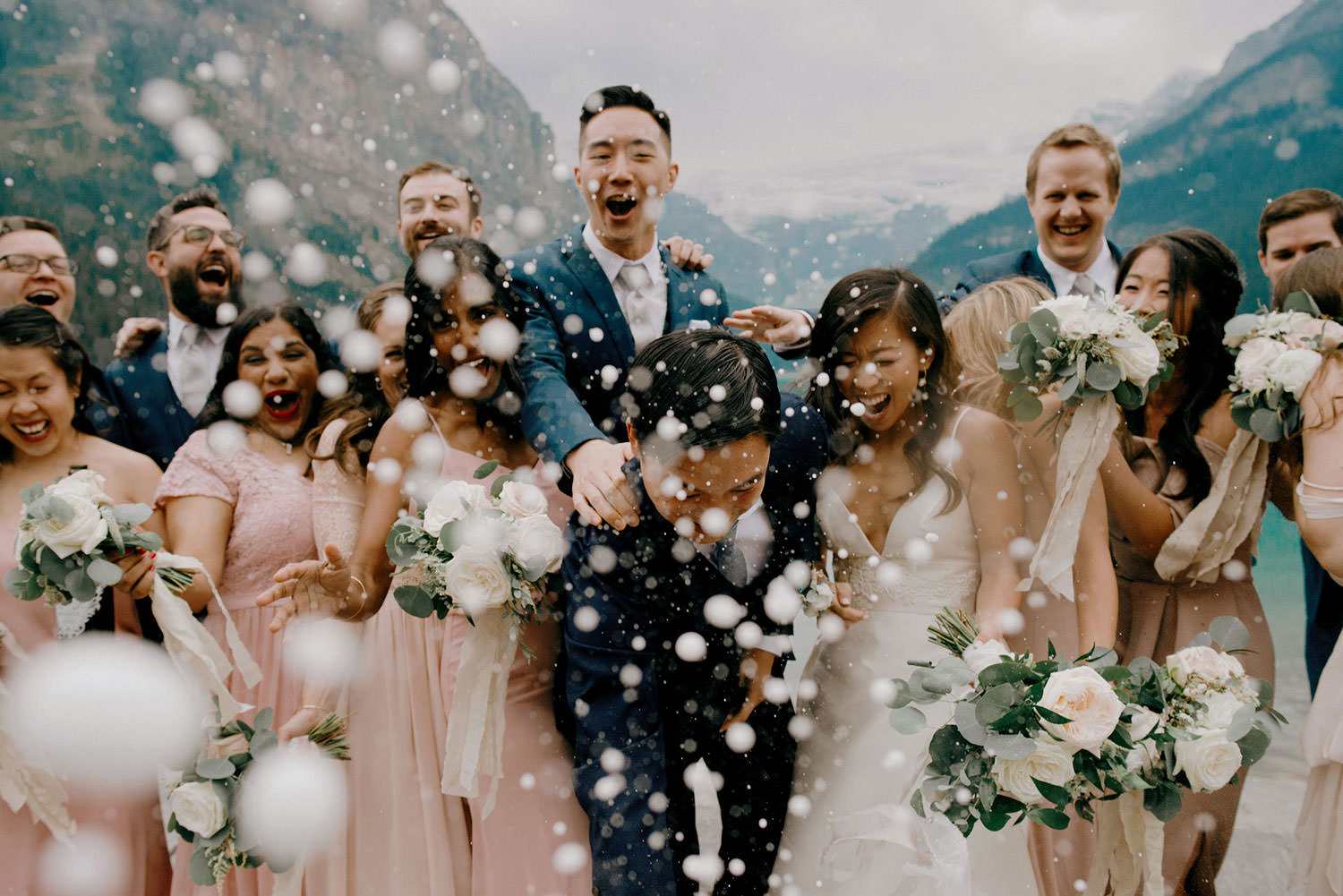 bridal party pops and sprays champagne bottle at the fairmont chateau lake louise in Alberta