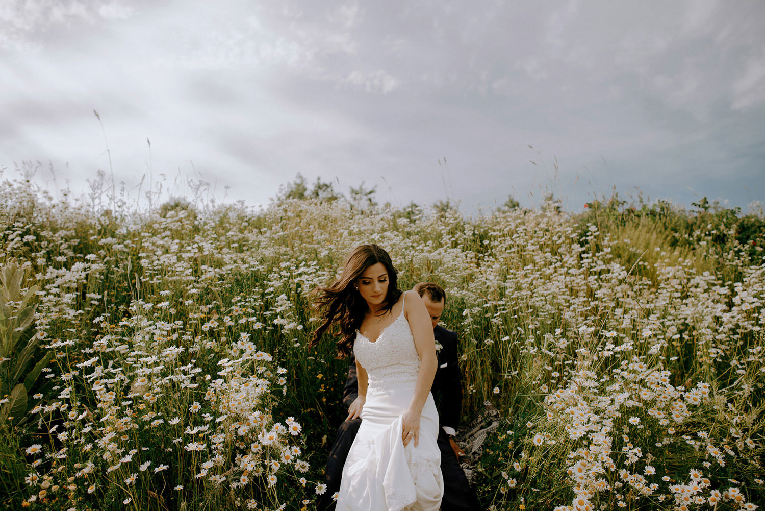 Science North Ontario Wedding photography of bride emerging from the wild flowers with her husband behind her