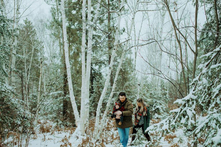 family walks in wintery forest in sudbury Ontario for a family photography session