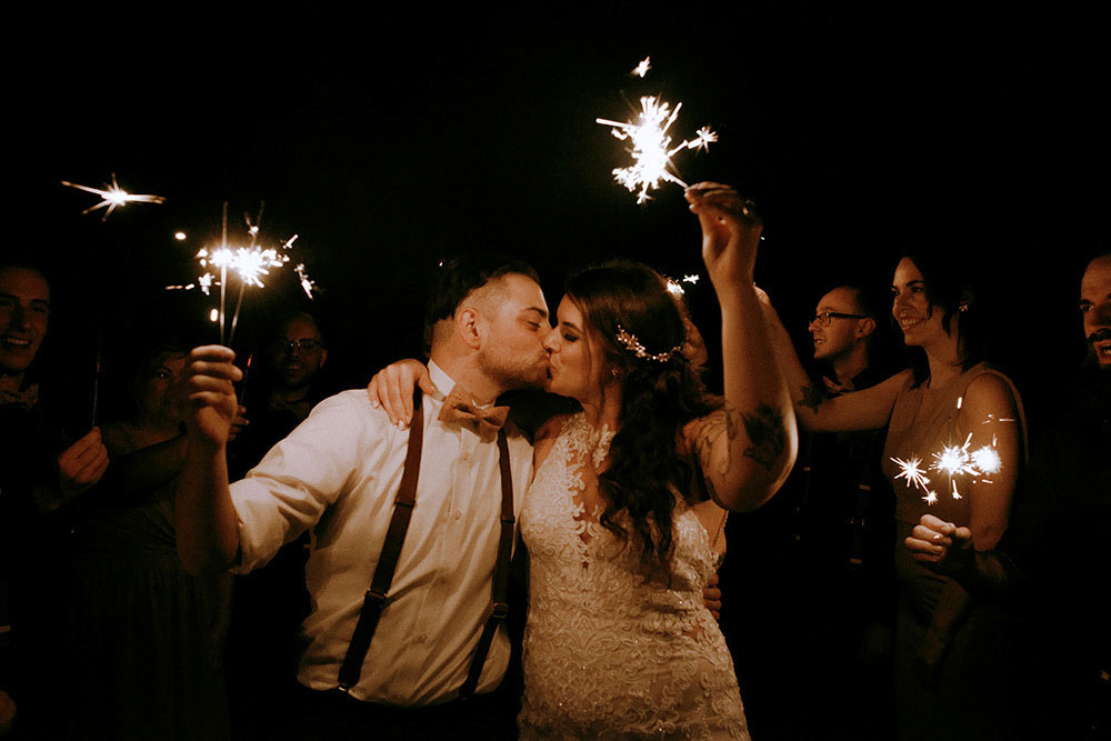 Best Wedding reception Photography of sharing a kiss while holding sparklers