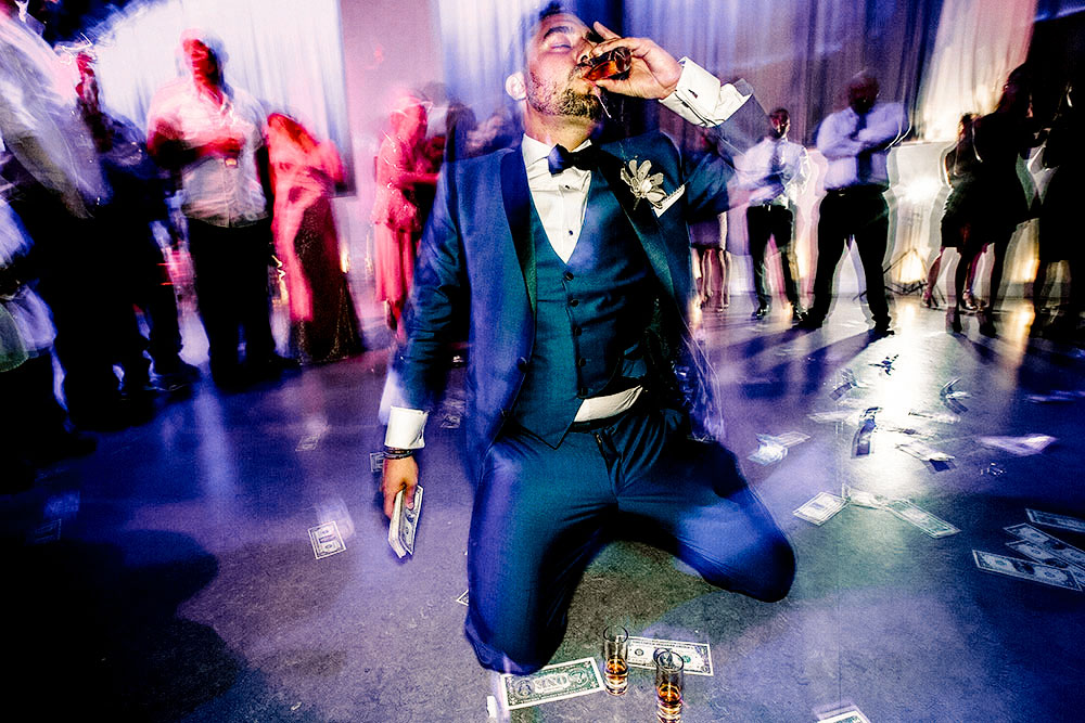 Best Wedding reception Photography of groom taking a shot on the dance floor