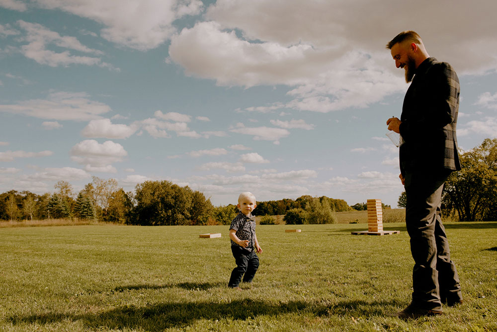 little boy plays lawn games with dad at this outdoor summer wedding at the heritage view barn