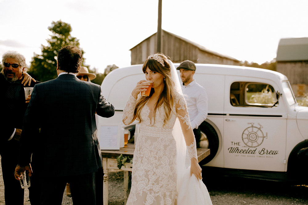 bride sips her berr in front of the wheeled brew at the heritage view barn