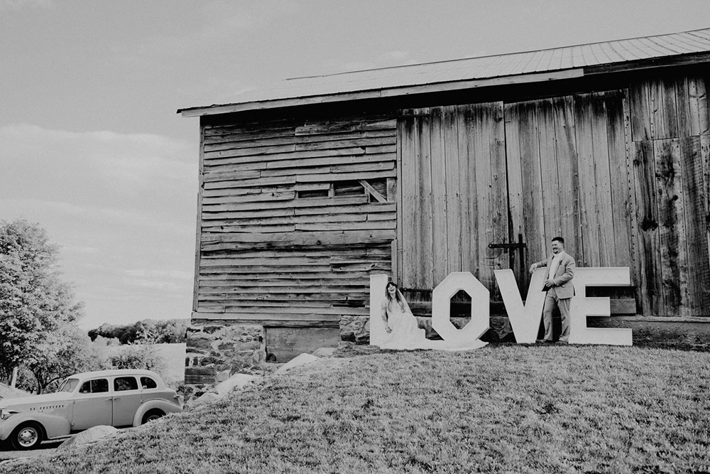 man poses with large LOVE sign in front of the heritage view barn