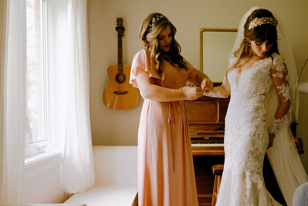 a bridesmaid helps the bride with the final touches before her ceremony
