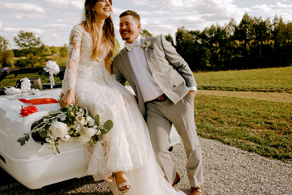 newlyweds sitting on a car at Heritage View Barn Wedding