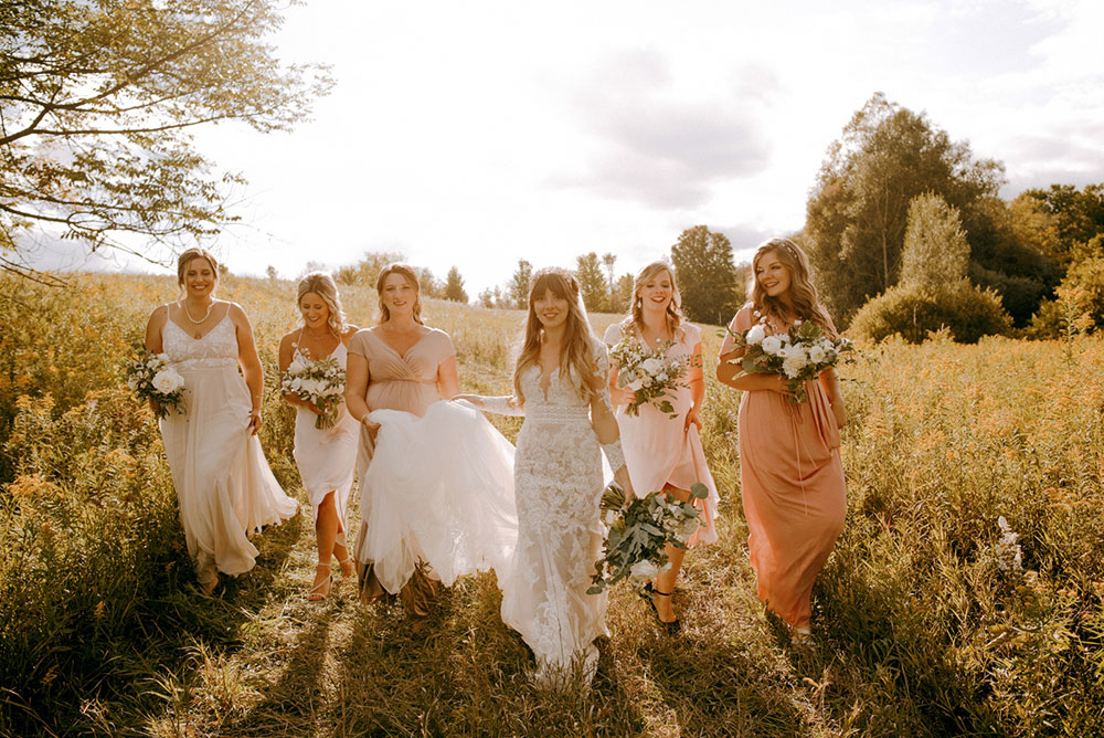 a bride and her bridesmaids walk toward the camera with flower bouquets in hand  at the heritage view barn
