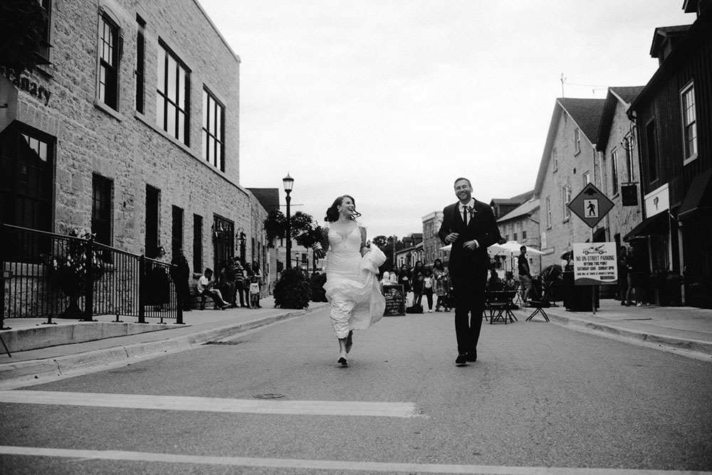 elora mill hotel elopement bride and groom dance through the downtown as husband and wife