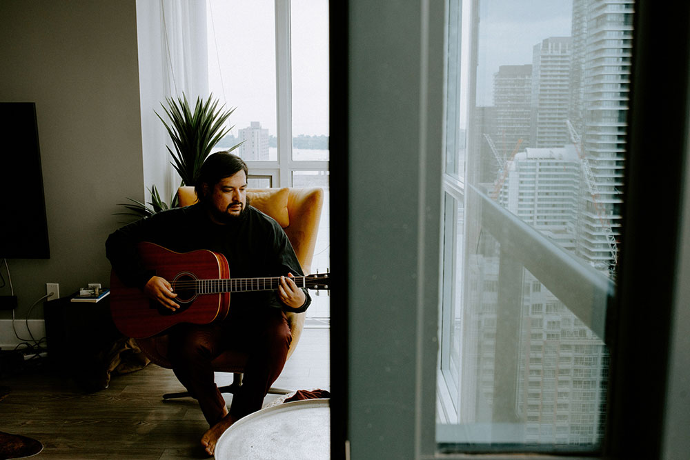 The Burroughes Toronto Wedding groom plays guitar in his condo before getting ready