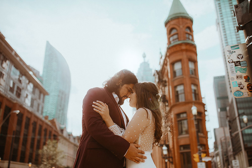 The Burroughes Toronto Wedding Couple stand in front of the Gooderham Building in Toronto