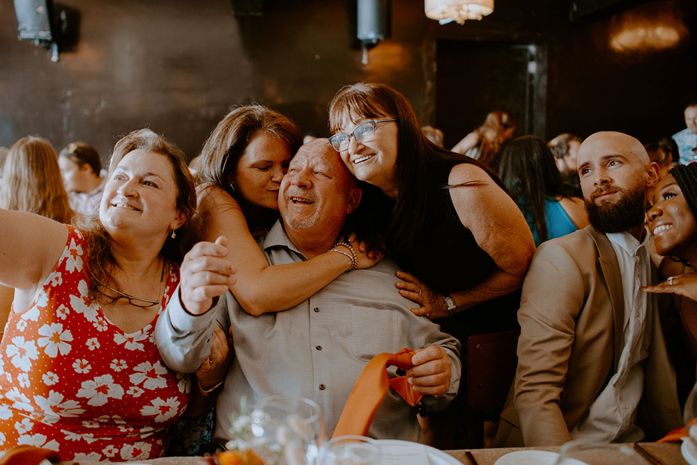 family embrace & pose during a selfie at respect is burning wedding reception