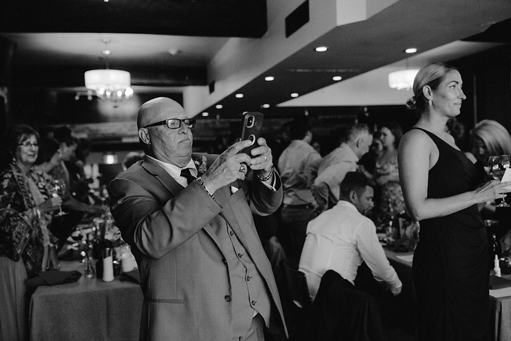 Man takes a photo with his cell phone at a wedding reception held at respect is burning kitchen in sudbury
