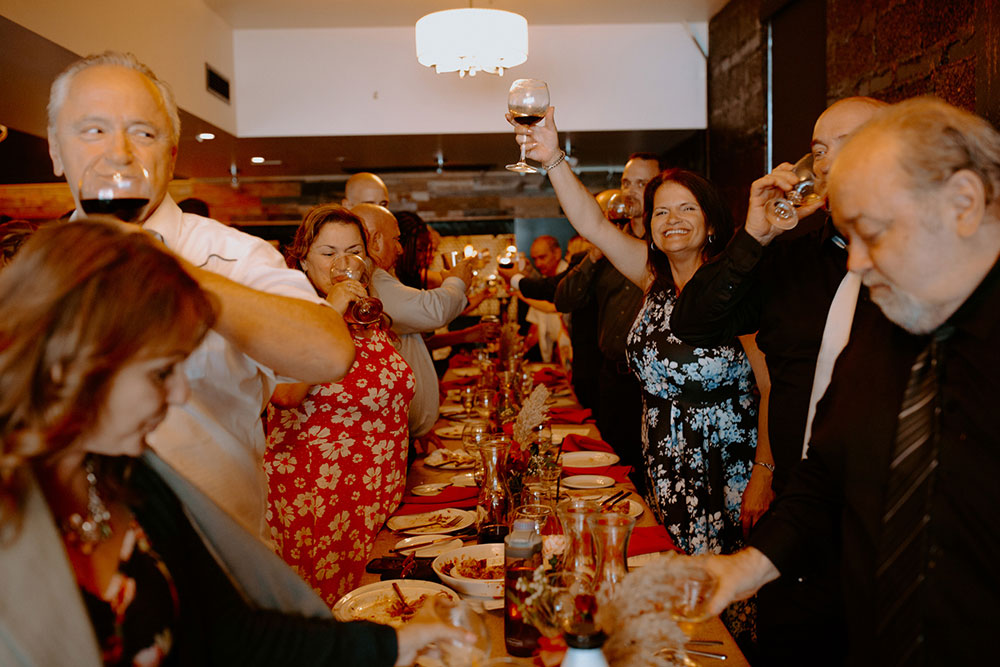 table of wedding guests raise their glasses to cheers the newlyweds at their reception held at respect is burning kitchen in Sudbury