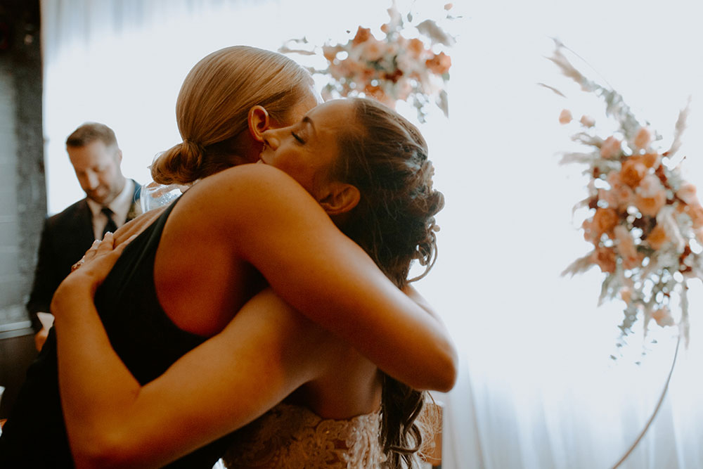 maid of honour & Bride embrace at respect is Burning Kitchen in Sudbury