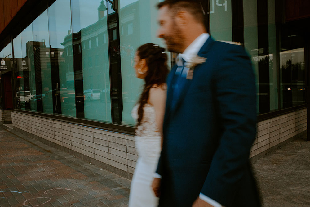 blurry image of wedding couple as the walk past the places des artes in Sudbury 