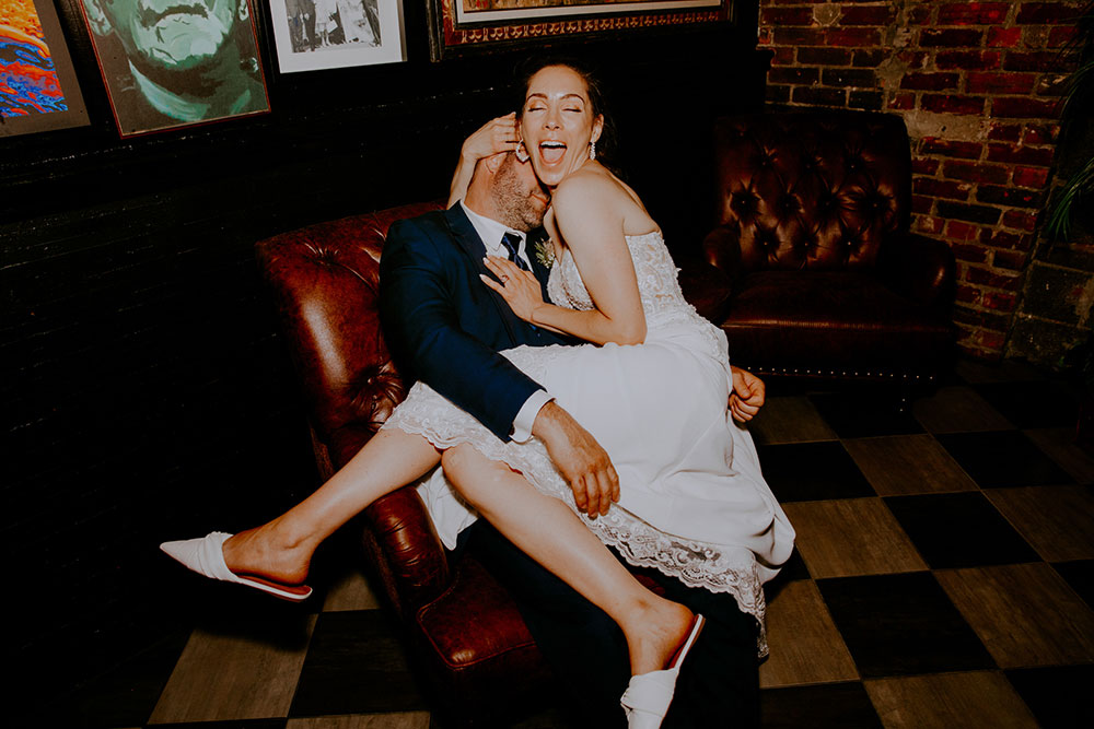 Newlyweds pose in front of wall of art at respect is burning kitchen