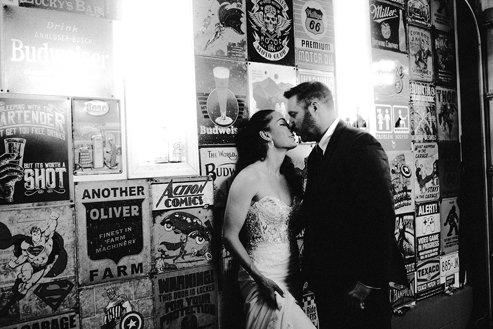 newlyweds kiss in garage full of vintage signs