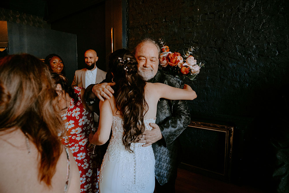 father embraces his daughter after the wedding ceremony at the cedar nest in Sudbury