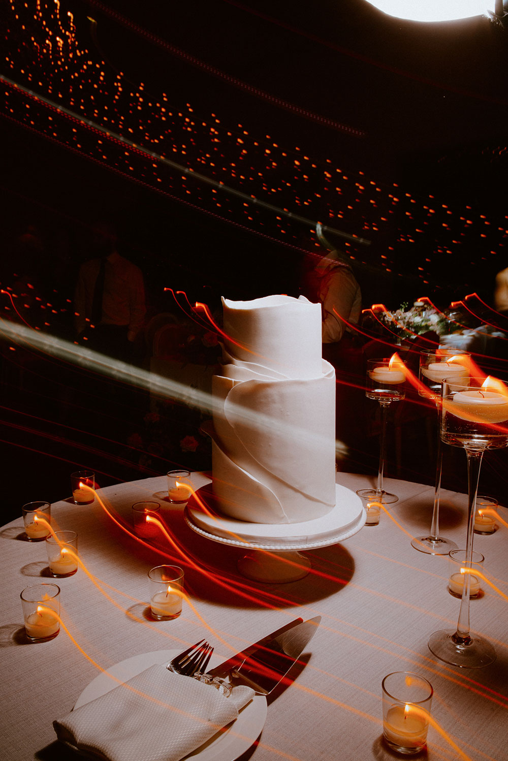 fun swirls of candlelight shoot across across the wedding cake created with a shutter drag at this Arlington Estate wedding