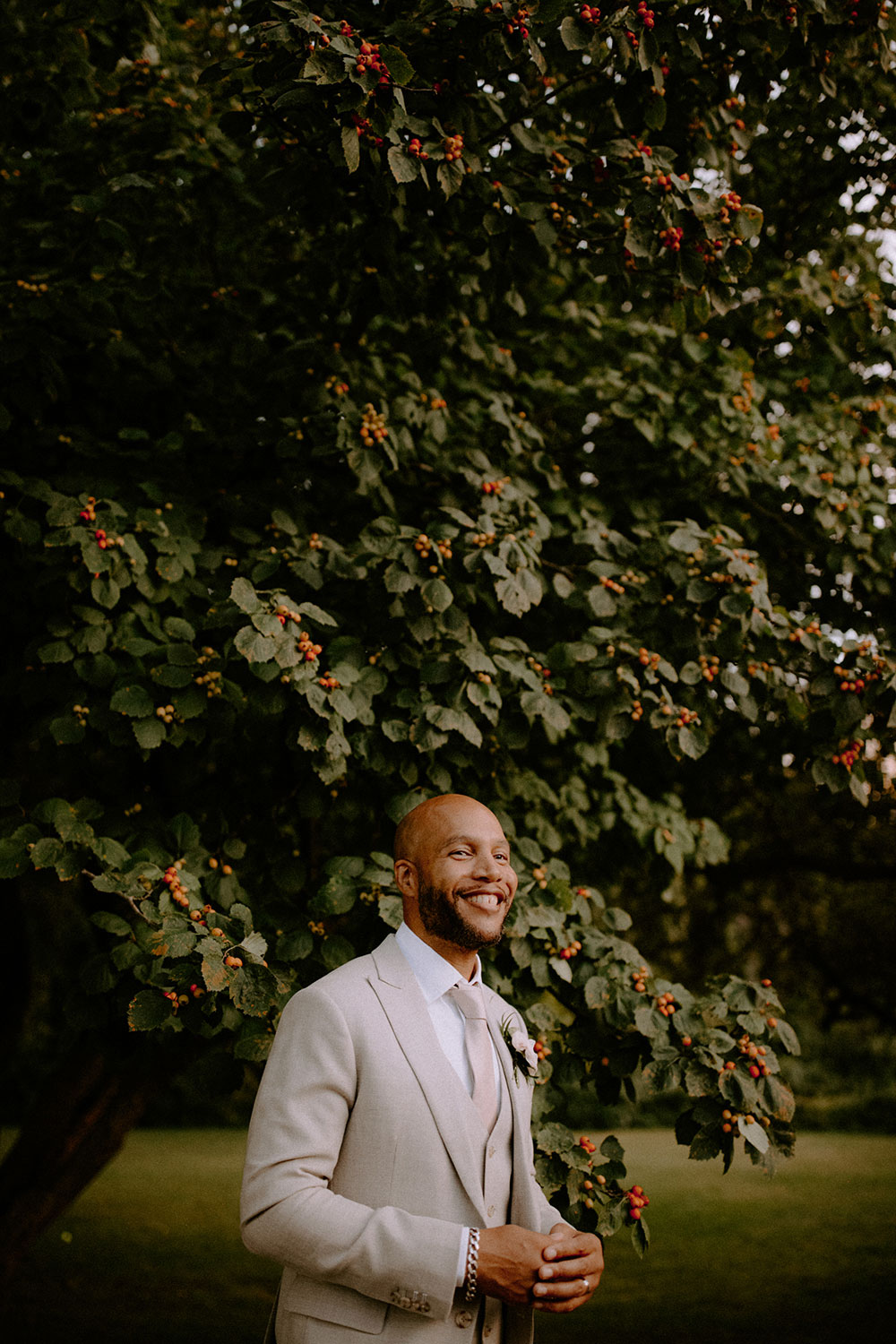 groom smiles by a berry tree at this Bayview Golf Wedding