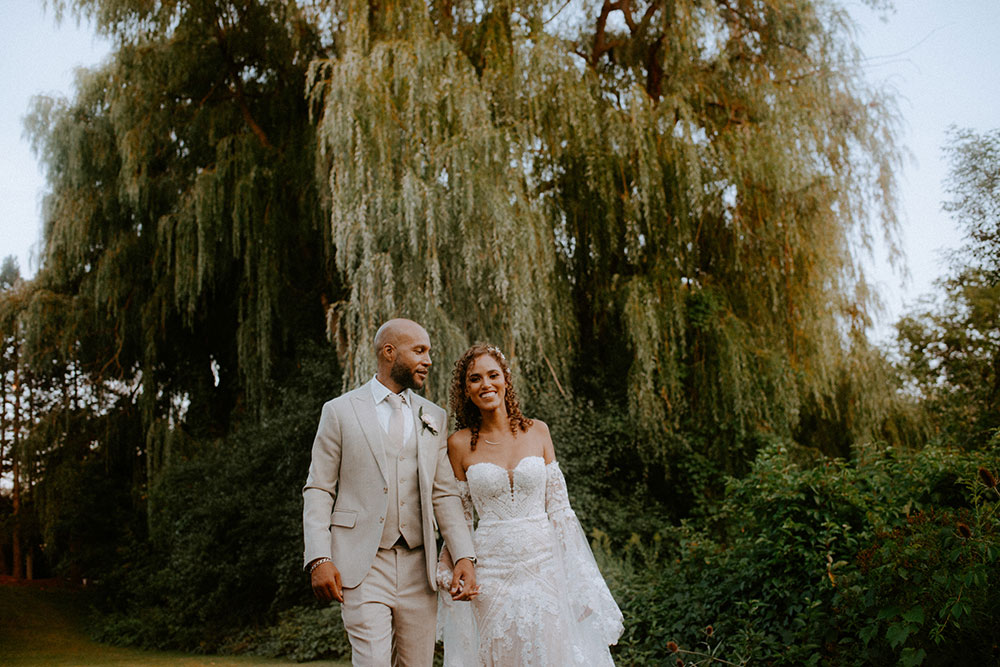 newlyweds walk under a willow tree at this Bayview Golf Wedding