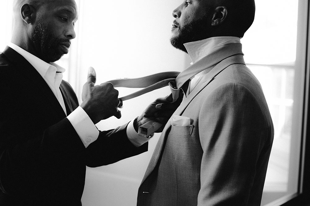 groomsmen helps groom with his tie at this Bayview Golf Wedding