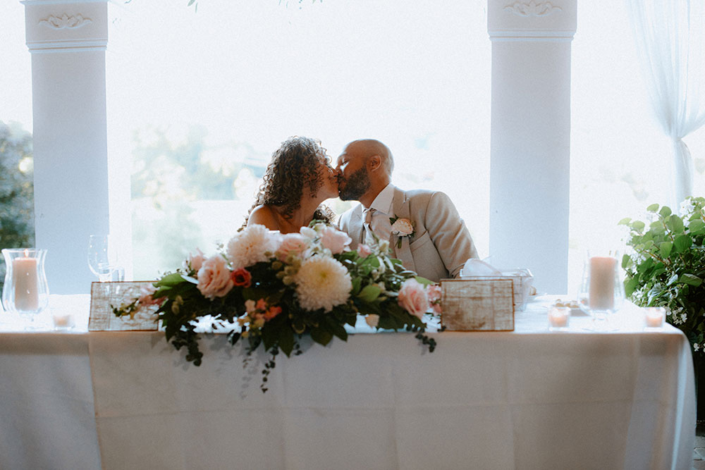 bride and groom kiss at the head table at this Bayview Golf Wedding