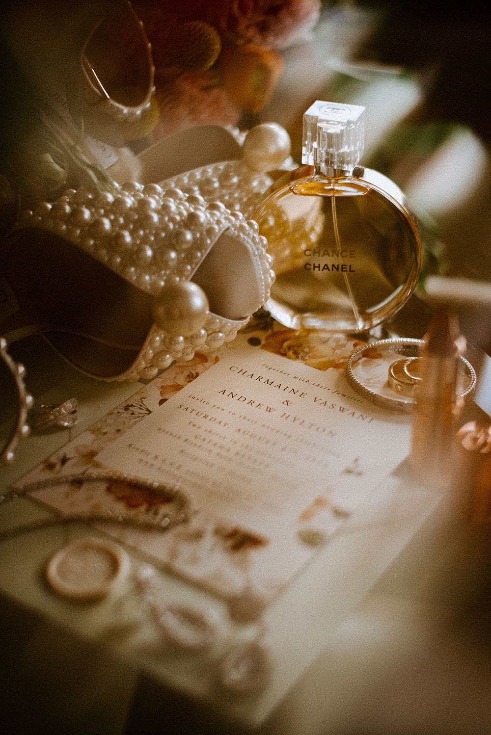 detail photos of wedding invitation along with jewelry and a bottle of Chanel Parfum