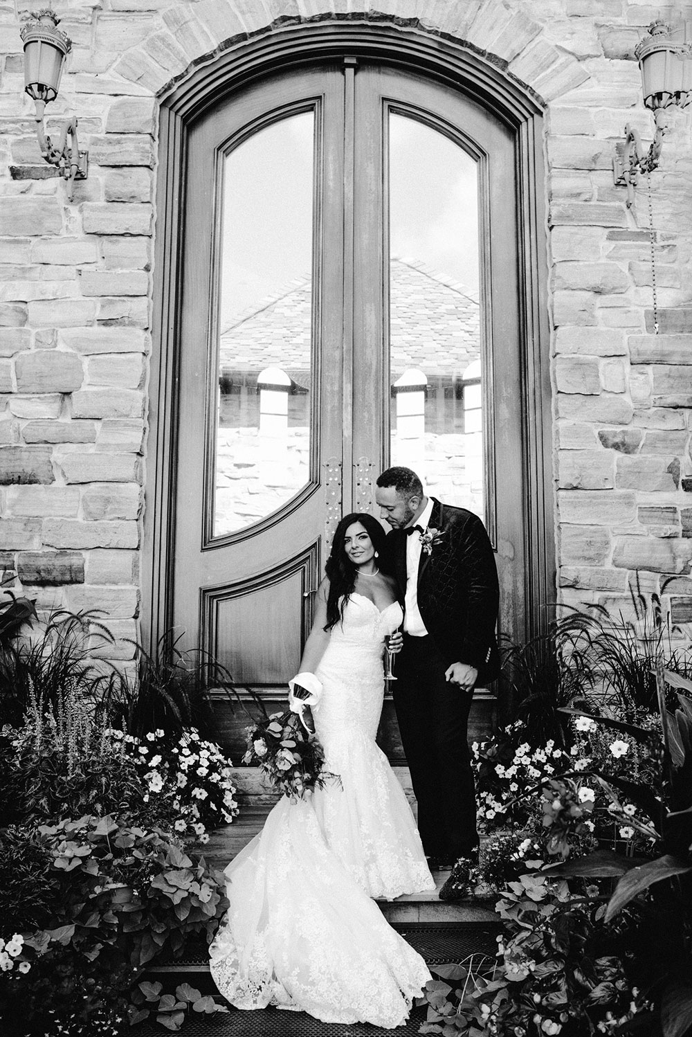 husband and wife pose in front of grand door at the Catana Estate