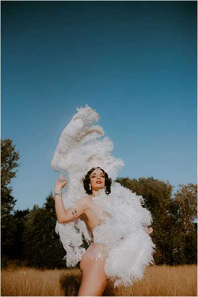 starlotte the burlesque performer in the middle of the field with big feathers