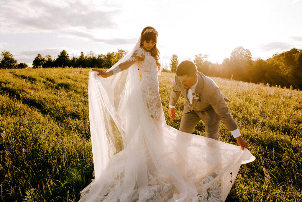 Stunning bride in a lace dress adjusts her veil at her luxury wedding alongside her groom as captured by their Toronto wedding photographers