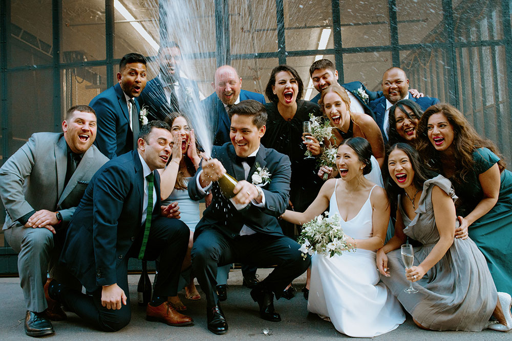 mildred's temple kitchen wedding photography of the wedding couple sharing a champagne pop with their wedding party 