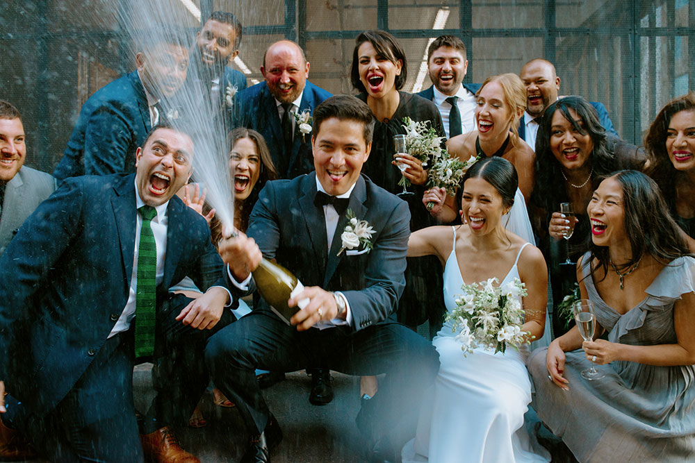 mildred's temple kitchen wedding photography of the wedding couple sharing a champagne pop with their wedding party 