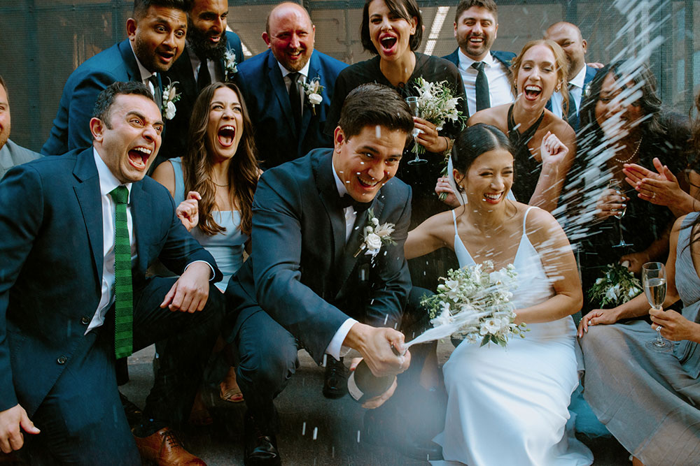 mildred's temple kitchen wedding photography of the wedding couple sharing a champagne pop with their wedding party 