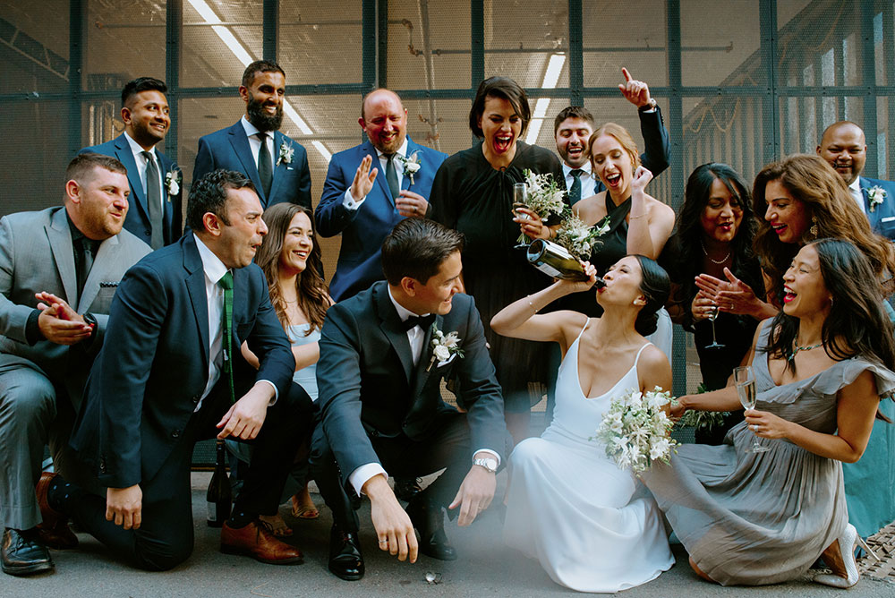 mildred's temple kitchen wedding photography of the wedding couple sharing a champagne pop with their wedding party 