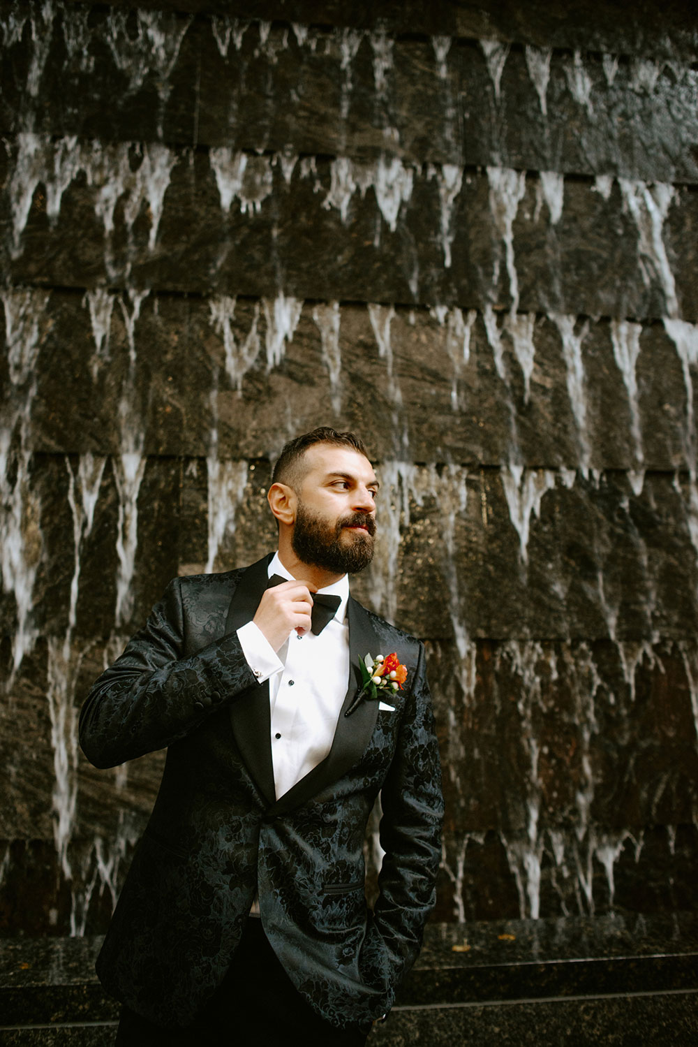 Sassafraz Yorkville Wedding Photography of the wedding couple posing candidly in front of a water wall attached to the Four Seasons in Yorkville