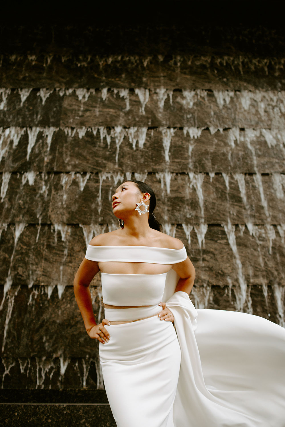 Sassafraz Yorkville Wedding Photography of the wedding couple posing candidly in front of a water wall attached to the Four Seasons in Yorkville