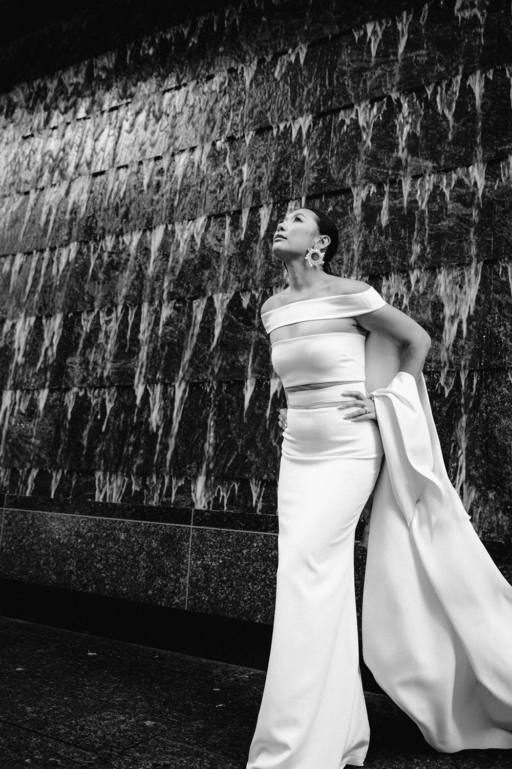 Sassafraz Yorkville Wedding Photography of the wedding couple posing candidly in front of a water wall attached to the Four Seasons in Yorkville