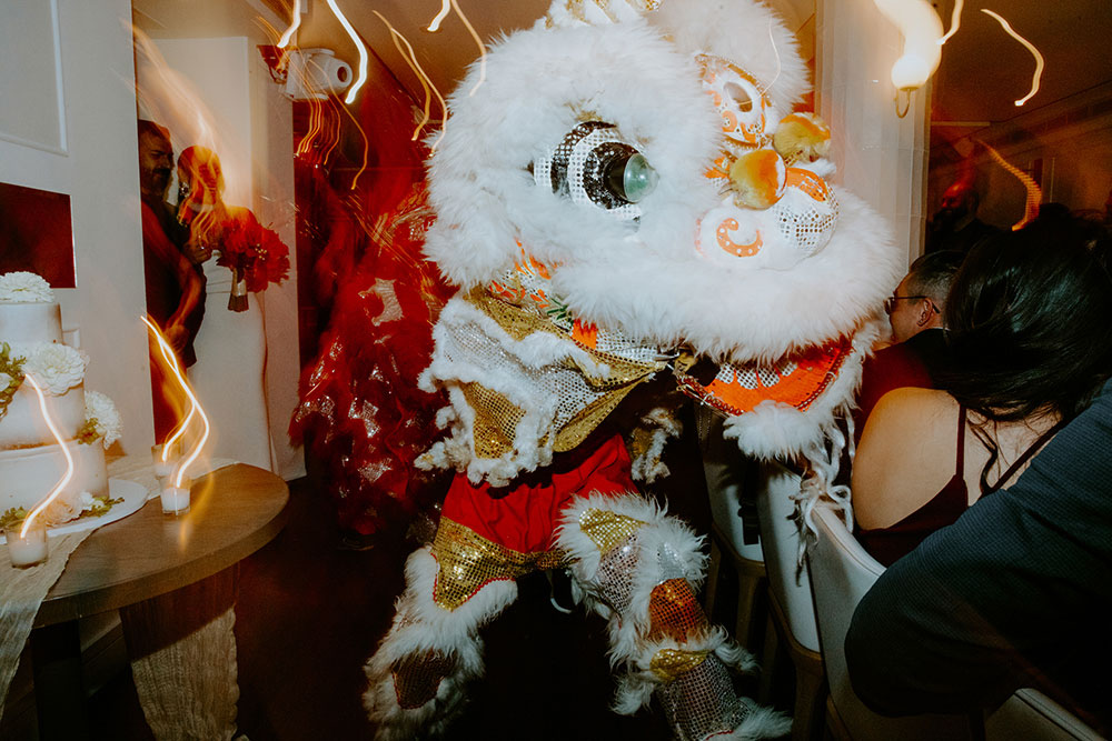 Sassafraz Yorkville Wedding Photography of the wedding couple walking into the wedding reception followed by lion dancers