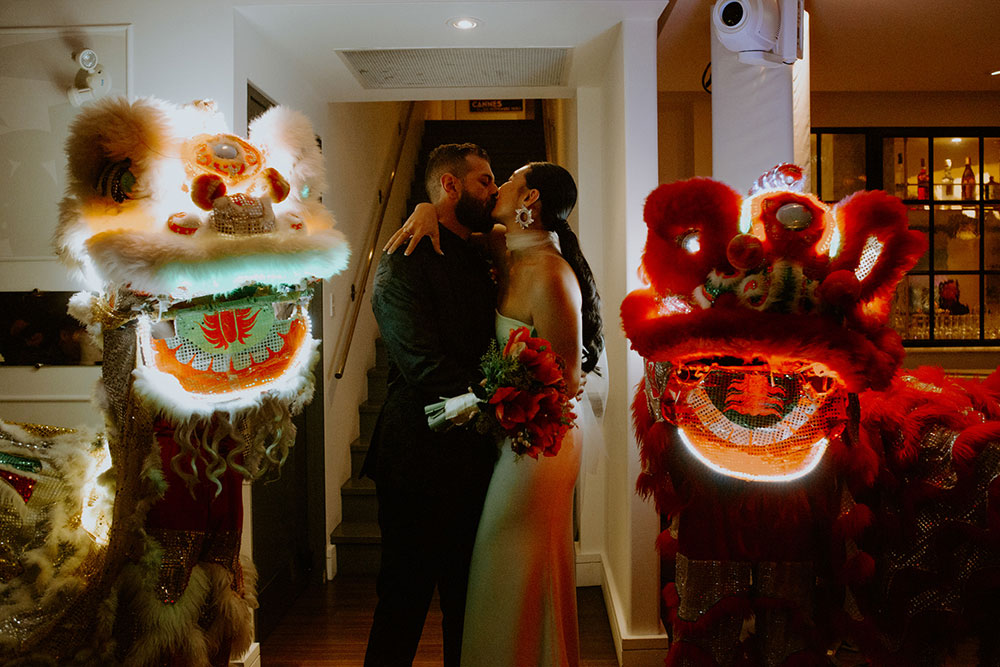 Sassafraz Yorkville Wedding Photography of the wedding couple kissing during the wedding reception followed by lion dancers