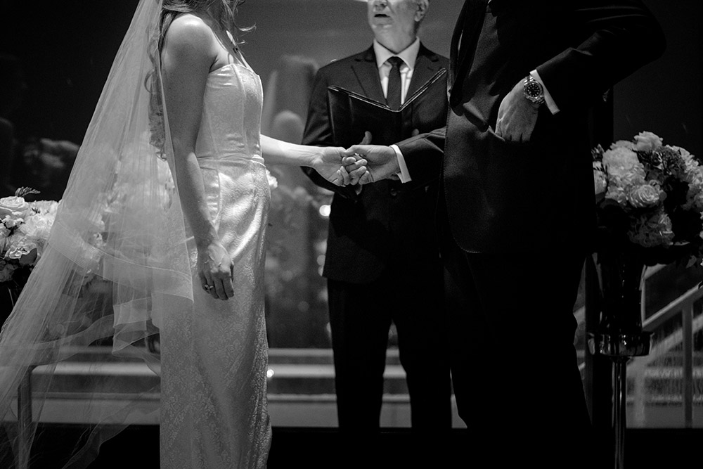 Bride and groom hold hands during their ceremony at their Antonio Park wedding in Toronto